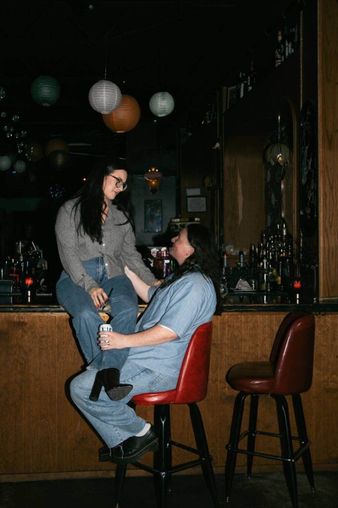 Regan and Kenzie sharing a glass of wine during a winter engagement session in Dallas Fort Worth
