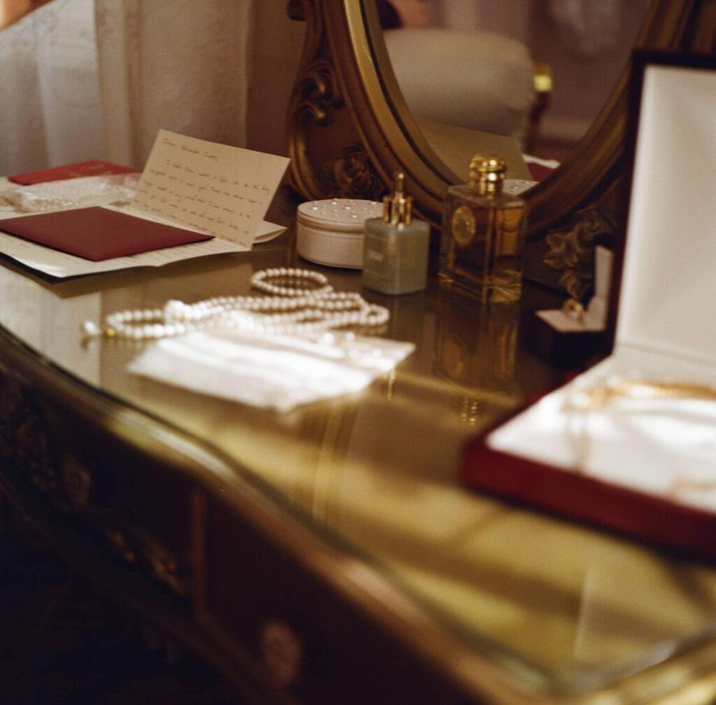 Flat lay of wedding invitation suite, heirloom jewelry, and bridal accessories